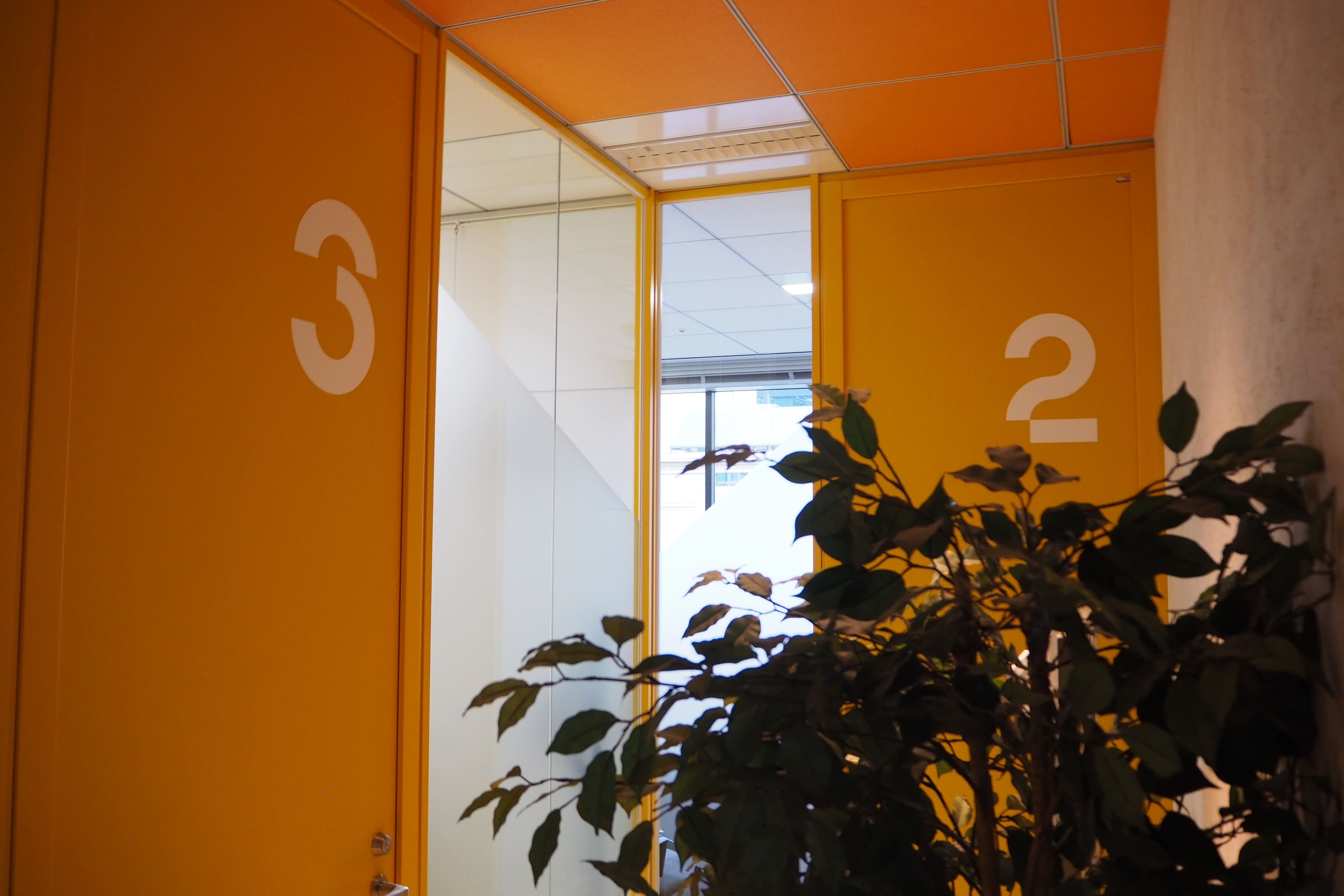 コーポレートカラーのオレンジを扉にあしらった会議室